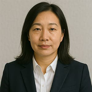 A woman in a suit is smiling while posing for a headshot against a plain background. She has an elegant blazer on and is looking directly at the camera, showcasing her professional demeanor.