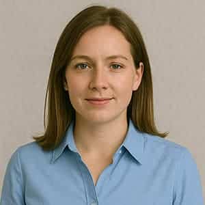 A woman in a blue shirt smiling against a plain wall, with her face prominently featured in a headshot.